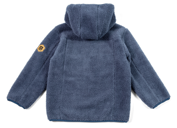 Blå Husqvarna Xplorer Kids luvtröja visad från framsidan, med en tydlig logo på ärmens övre del, placerad på en grön bakgrund.